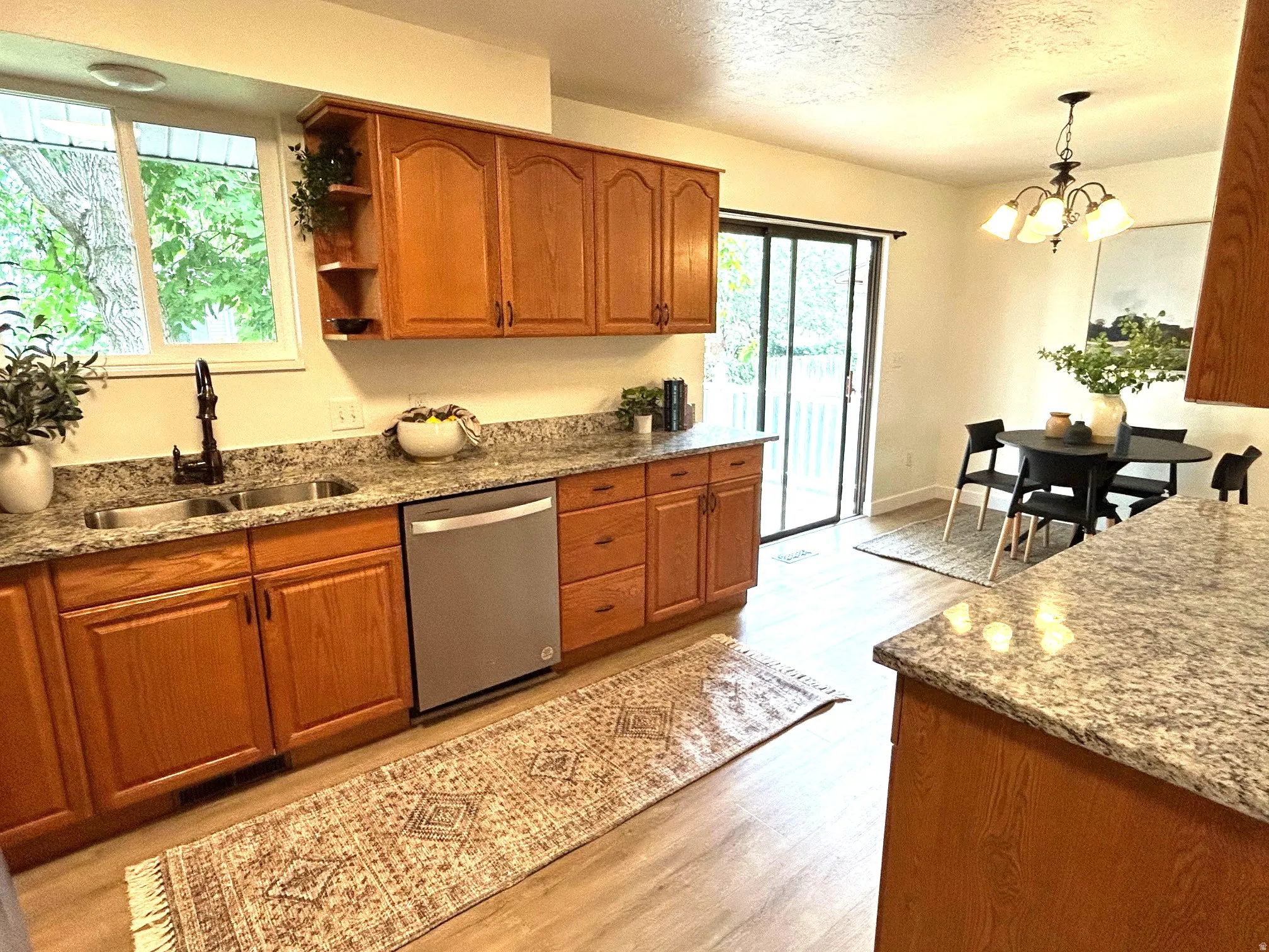 Kitchen featuring wood cabinetry, light-toned countertops, a stainless steel sink, and wood-finish flooring