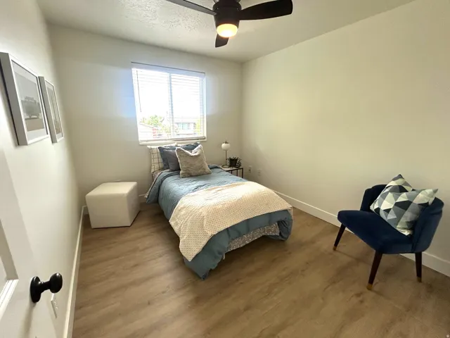 Wood-finish flooring, overhead ceiling fan with lighting, and a window with horizontal blinds