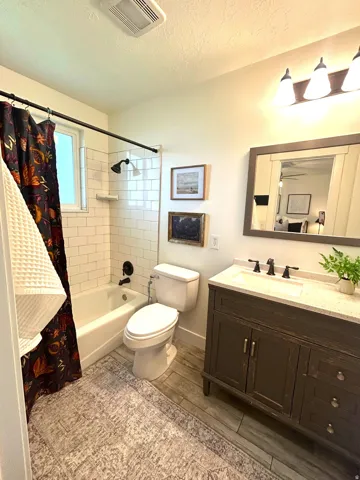 Single vanity with a light countertop, wood-finish flooring, white subway tile shower surround, and a tub/shower combination