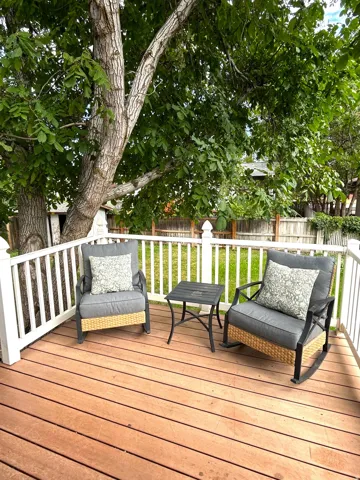 Expansive wood-finish deck with white baluster railing, offering a private outdoor extension