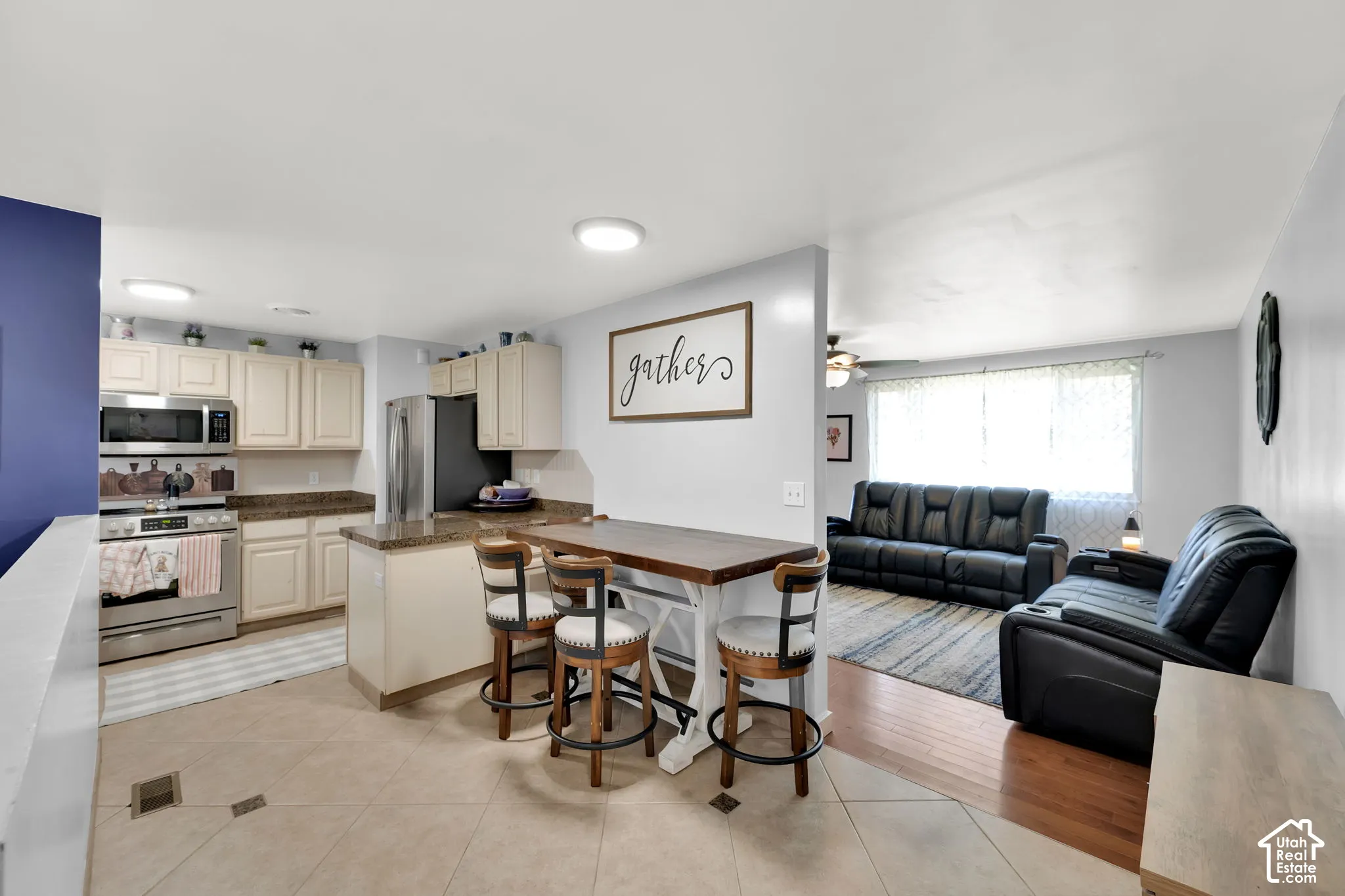 Kitchen featuring cream-colored cabinetry, stainless steel appliances, and a granite countertop island