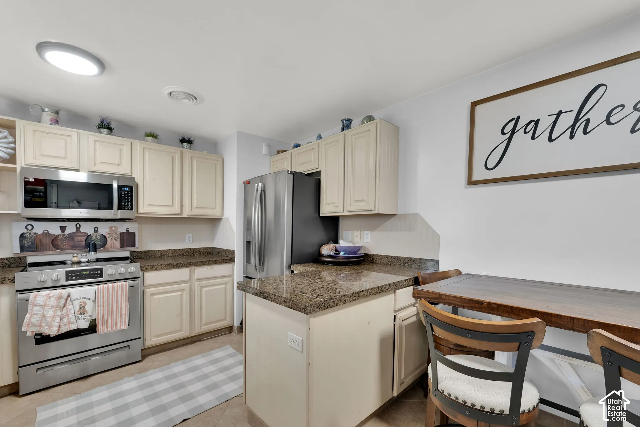 Kitchen featuring stainless steel appliances, cream cabinetry, and stone-finish countertops
