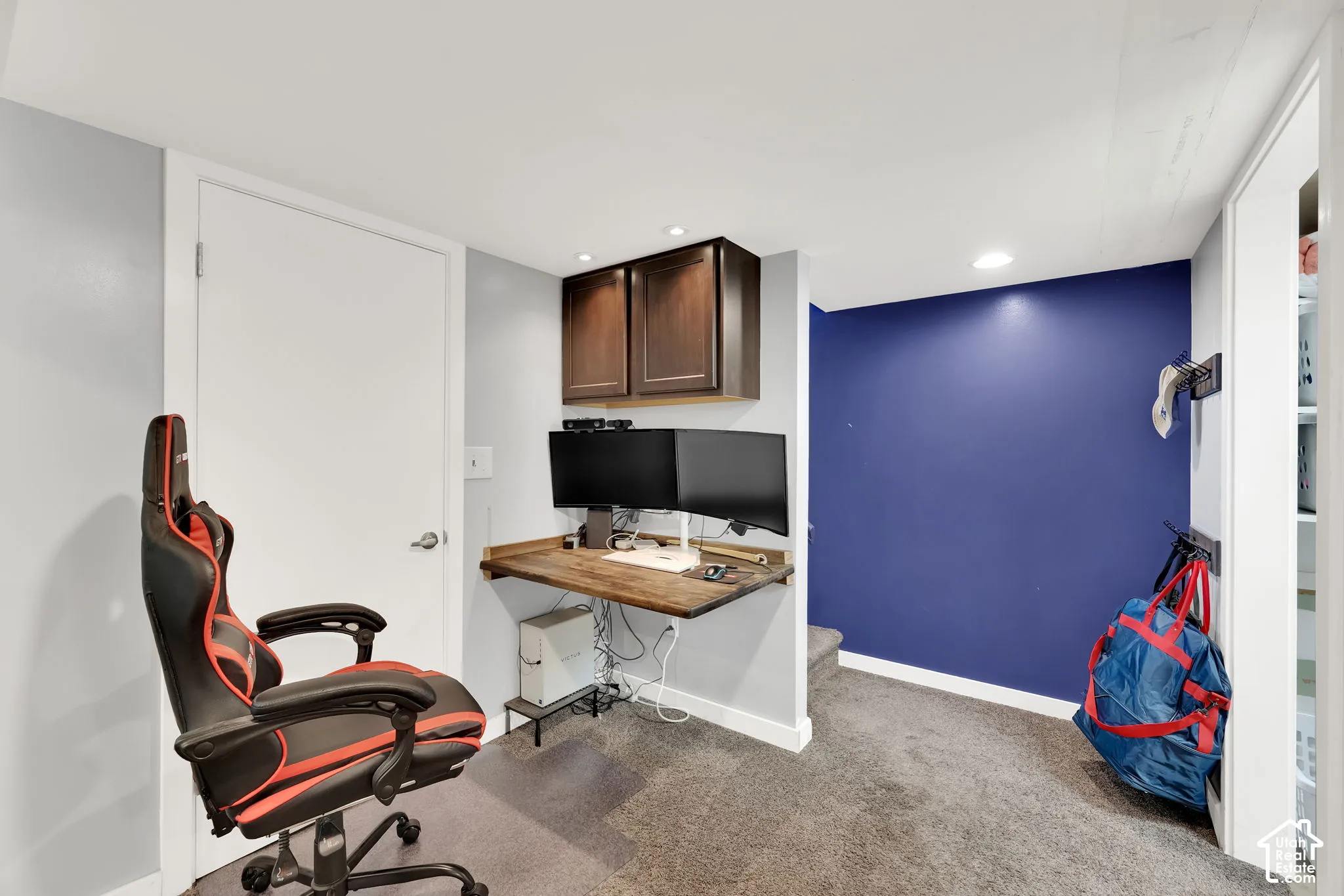 Built-in wood-finish desk with mounted cabinetry, recessed lighting, and carpet flooring