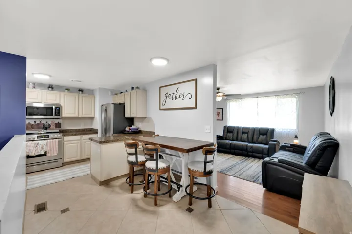 Kitchen featuring cream-colored cabinetry, stainless steel appliances, and a granite countertop island
