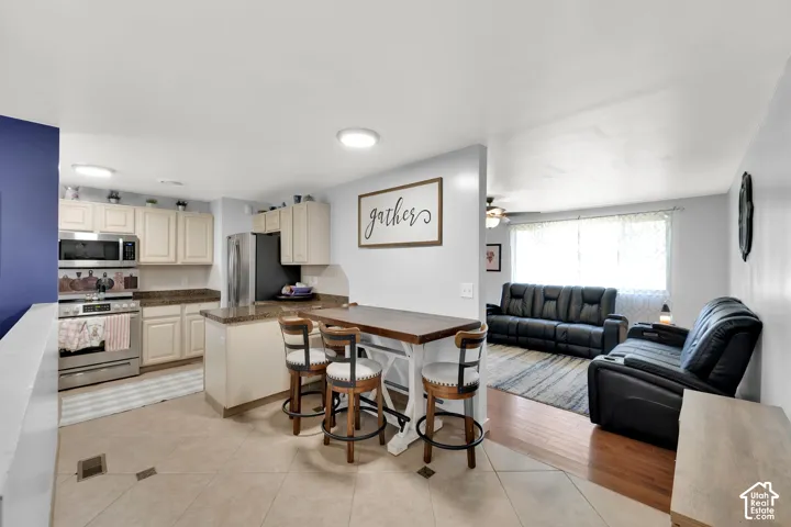 Kitchen featuring cream-colored cabinetry, stainless steel appliances, and a granite countertop island