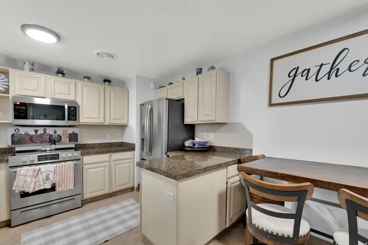 Kitchen featuring stainless steel appliances, cream cabinetry, and stone-finish countertops