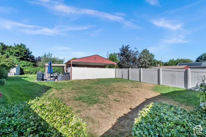 Expansive backyard featuring a privacy fence, covered patio, and mature landscaping