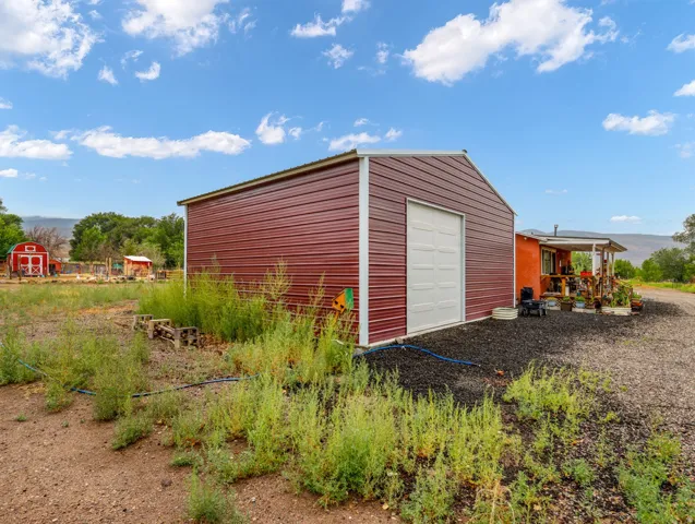 Red corrugated metal outbuilding with a white roll-up garage door