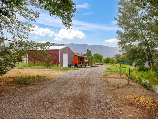 Gravel drive leading to a red metal utility building with a roll-up door