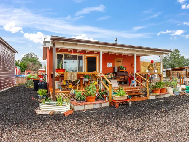 Covered porch with wood railing and steps, exterior siding, and a gravel ground cover