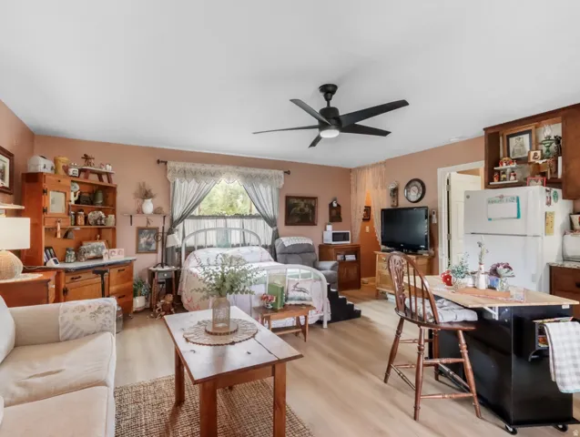 Light wood-finish flooring, a ceiling fan with light, and a window with natural light
