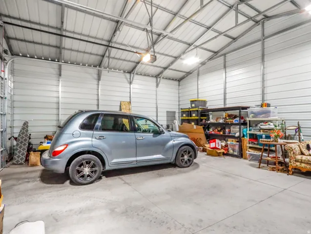 Spacious metal garage with a high vaulted ceiling, exposed metal framing, and concrete flooring