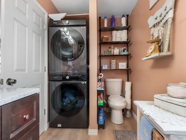 Stacked washer and dryer units, built-in shelving, and wood-finish flooring