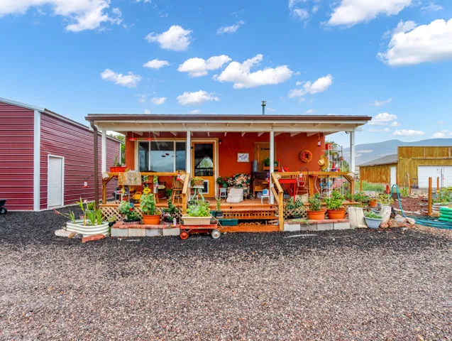 Property with a covered front porch, red-orange exterior, and a gravel driveway