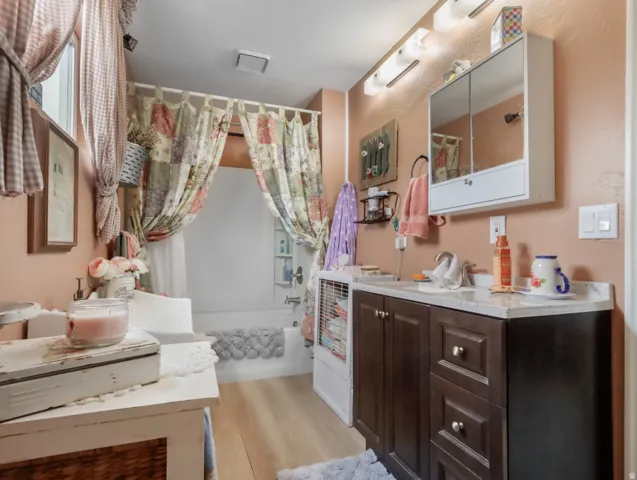 Wood-finish flooring with a vanity featuring a white countertop and an integrated sink