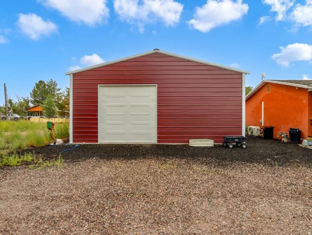 Red metal-sided outbuilding with white trim and a single garage door