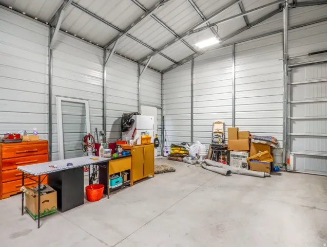 Metal building interior featuring corrugated metal walls, exposed steel framing, concrete flooring, and an overhead lighting fixture