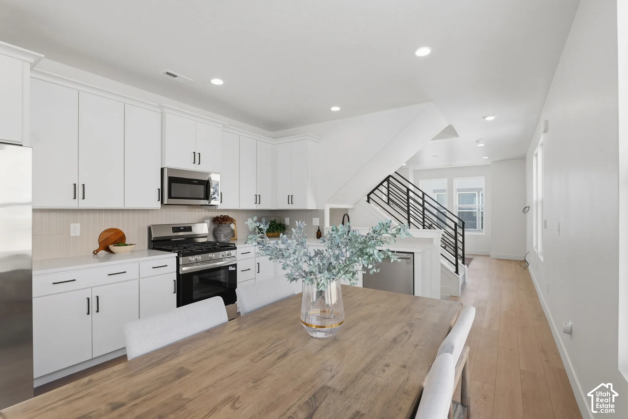 Modern kitchen with white cabinetry, stainless steel appliances, and a light-toned backsplash