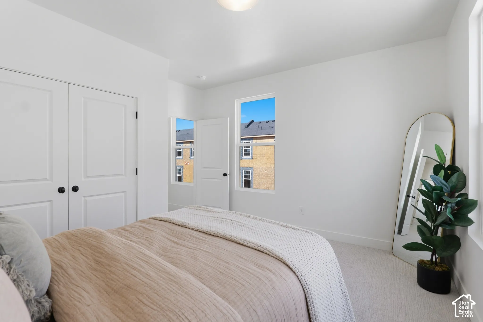 White wall paint throughout, double bi-fold closet doors with black hardware, white trim around windows, and light-toned carpet