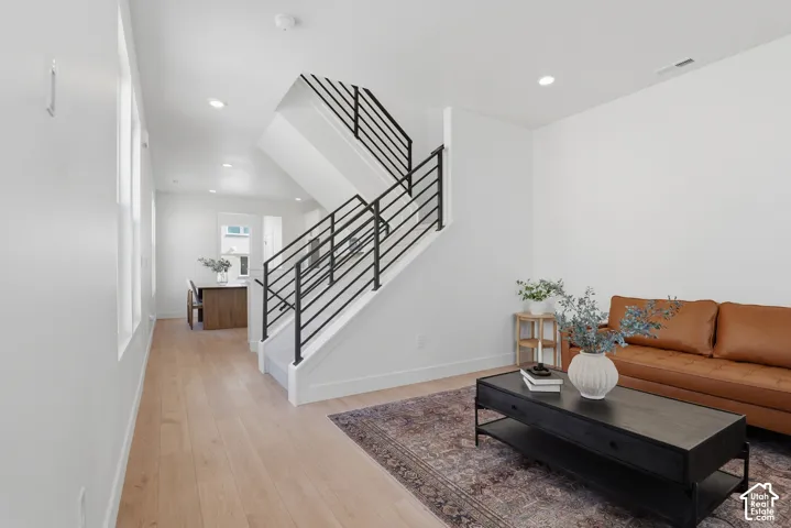 Light wood-finish flooring throughout, modern black metal stair railings, recessed lighting, and white wall finishes