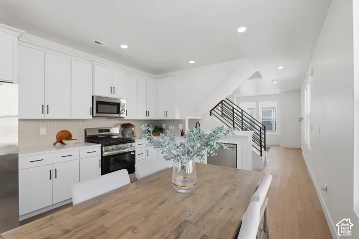 Modern kitchen with white cabinetry, stainless steel appliances, and a light-toned backsplash