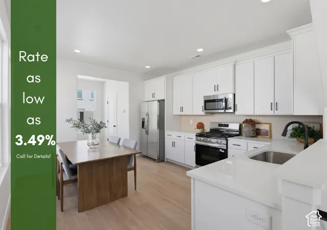 Kitchen featuring a stainless steel appliance suite, white cabinetry, light wood-finish flooring, and white countertops