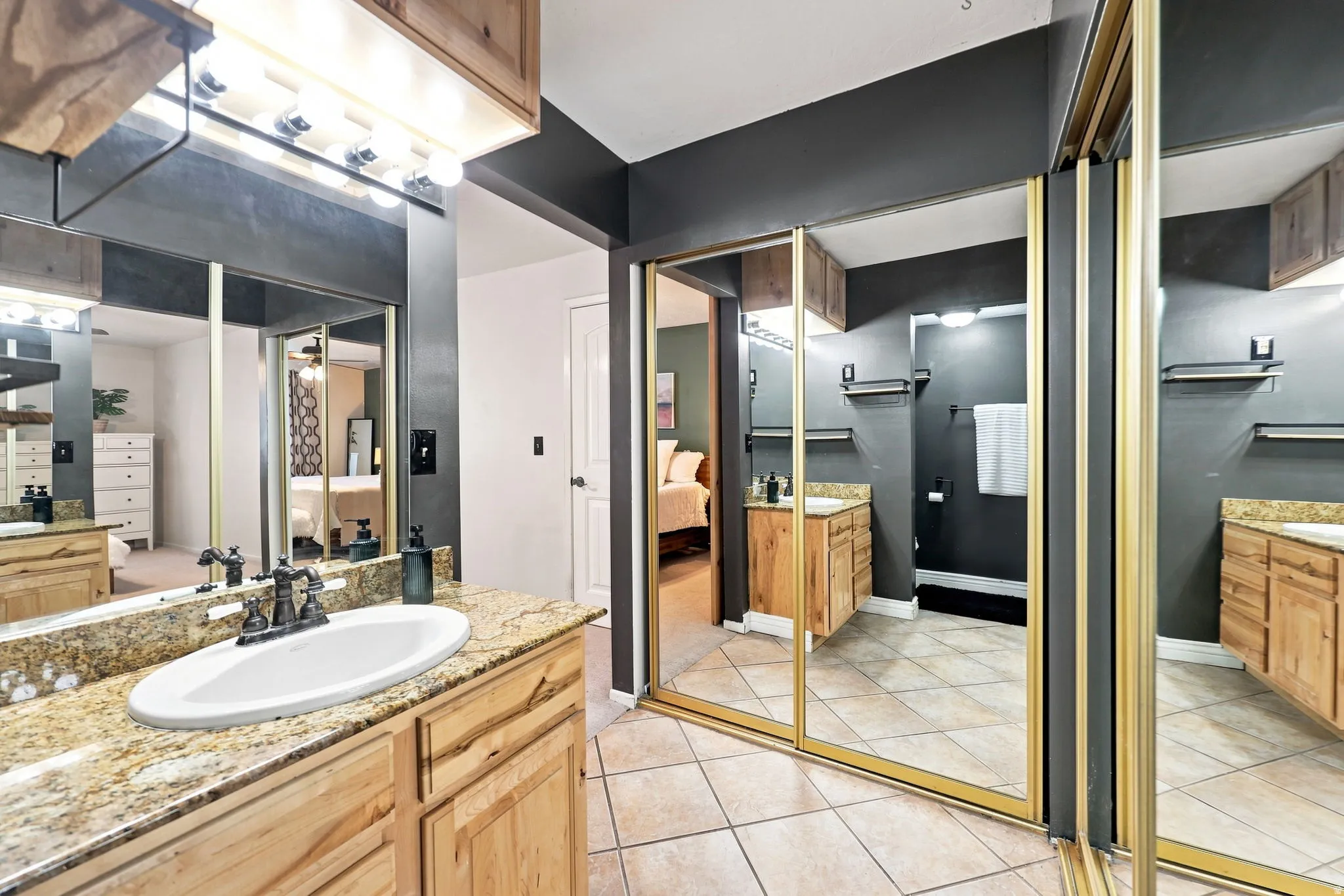 Light wood-finish cabinetry, granite-style countertop, and a vanity light fixture