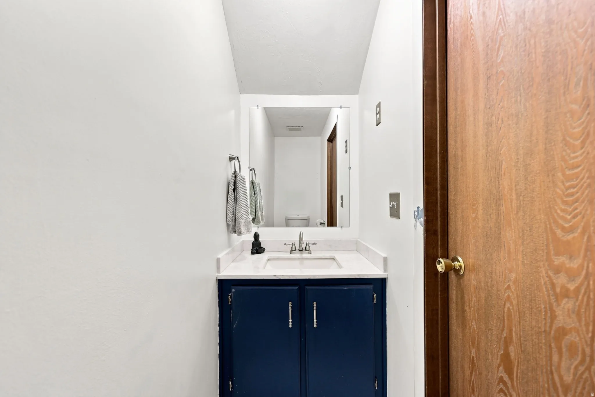 Vanity with an integrated sink, white countertop, and dark blue cabinetry