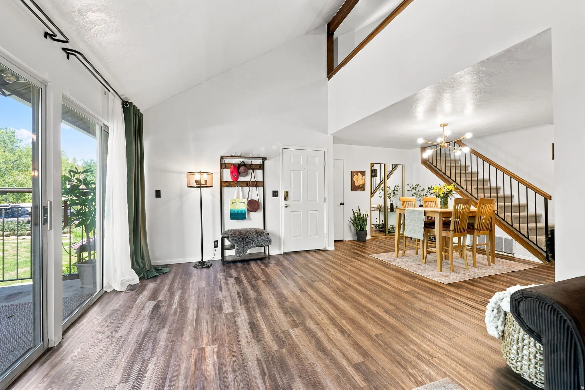 Vaulted ceilings, wood-finish flooring, sliding glass door, dining area, and open staircase with metal balusters