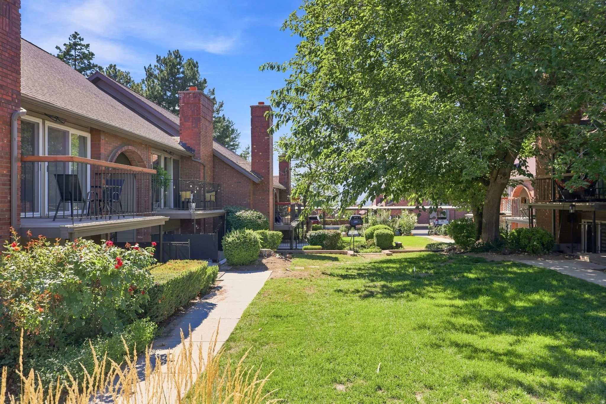 Brick exterior with multiple private balconies, featuring metal railings and wood-finish handrails