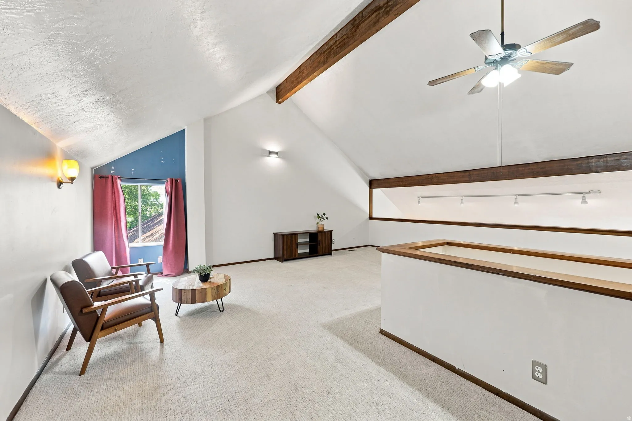 Vaulted ceiling with exposed wood beams, ceiling fan light fixture, recessed wall lighting, and interior balcony