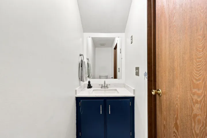 Vanity with an integrated sink, white countertop, and dark blue cabinetry