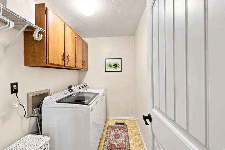 Laundry area featuring overhead wood-finish cabinetry, wire shelving, and beadboard panel door