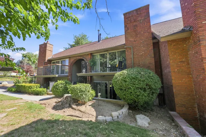 Brick exterior with multiple balconies, arched entryway, and mature landscaping