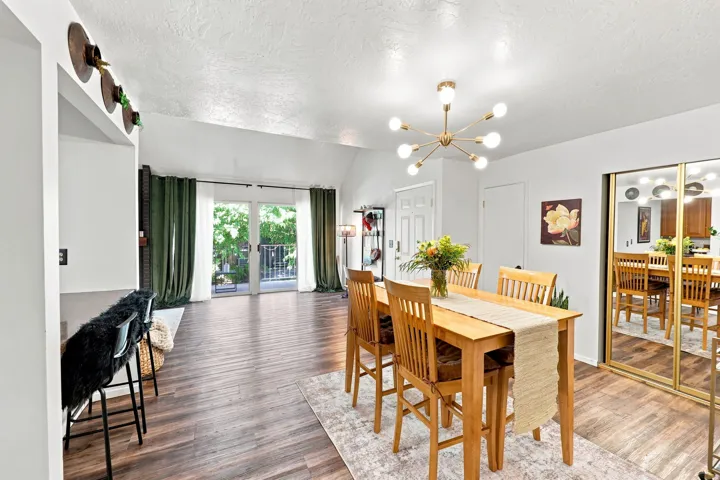 Vaulted ceilings, wood-finish flooring, gold-framed mirrored closet doors, and French doors leading to a balcony
