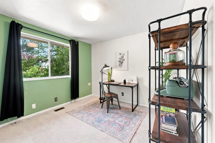 Carpeted flooring, window with natural light, flush mount ceiling light, and a built-in shelving unit with wood-finish shelves