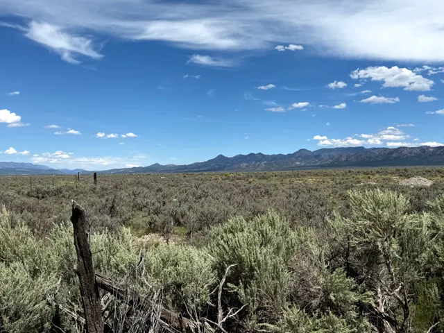 Expansive natural landscape with distant mountains under a blue sky with scattered clouds