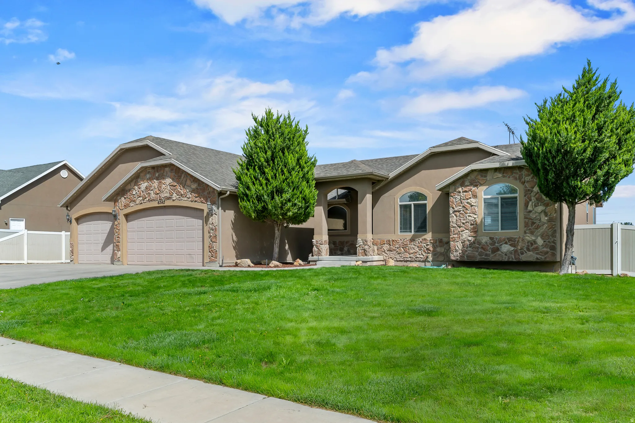 Stucco exterior with stone accents, arched windows, and a four-car garage