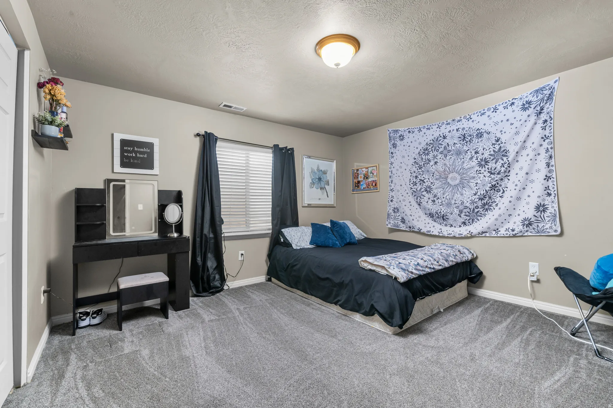 Carpeted flooring, window with blinds, wall-mounted light fixture, and neutral wall tones
