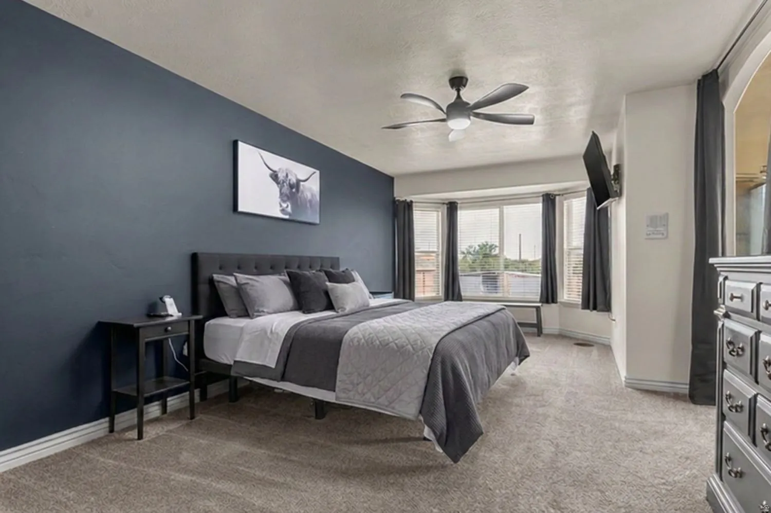 Accent wall, bay window, ceiling fan, carpet flooring, built-in shelving