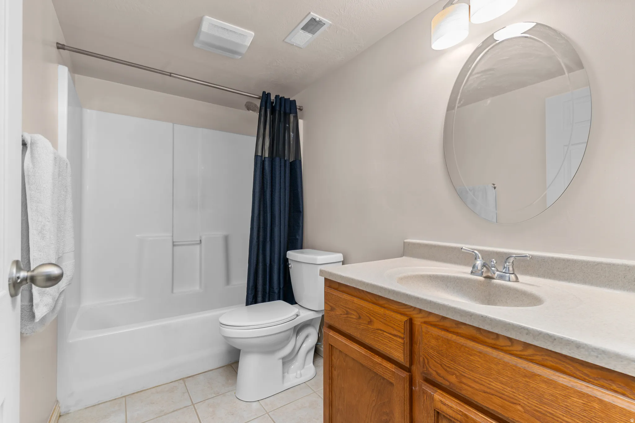 Full bathroom featuring a single vanity with wood cabinetry, a light-colored countertop, and an oval mirror