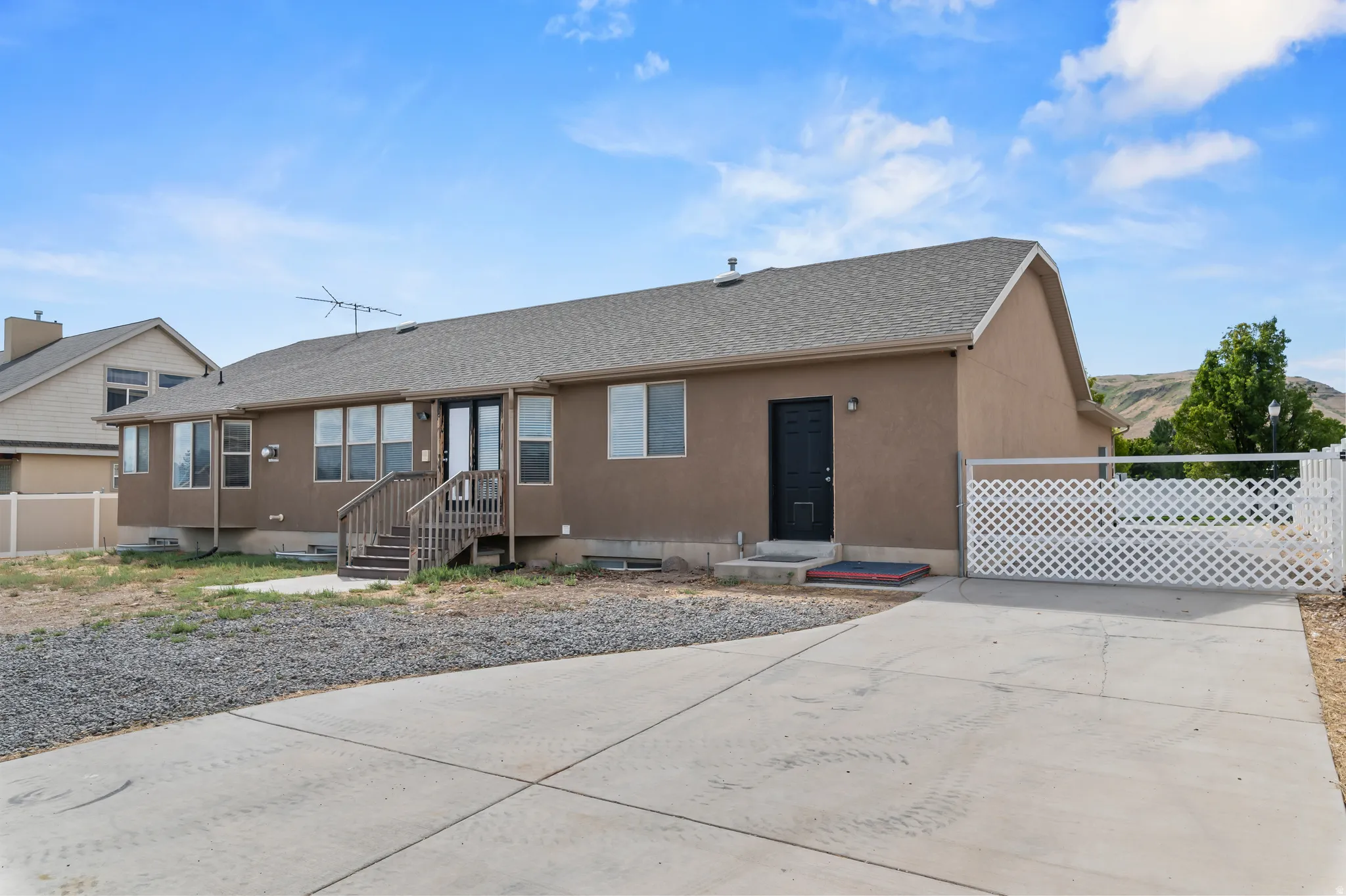 Concrete driveway, rear deck with wood steps, lattice fence, stucco exterior