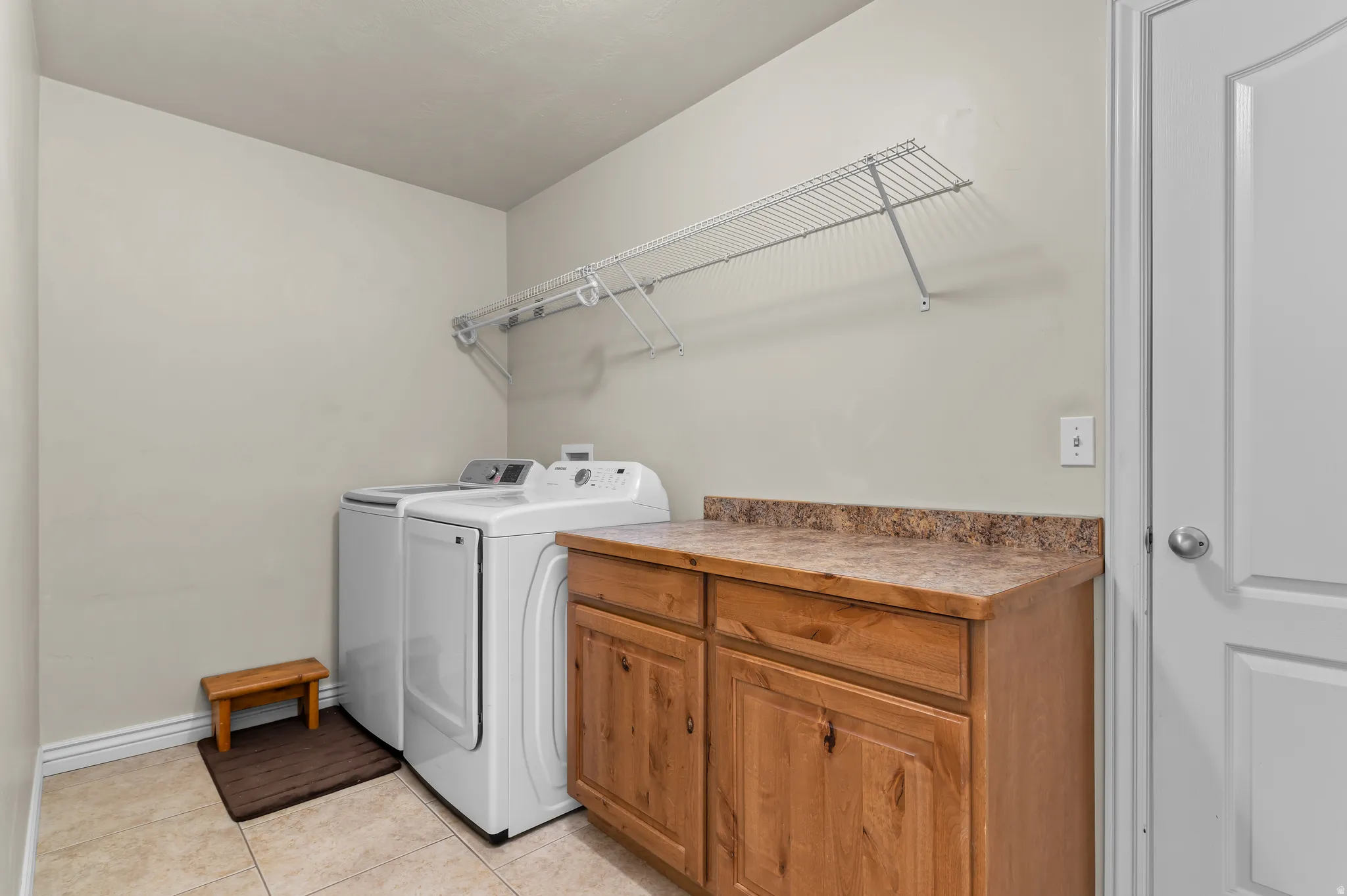 Built-in storage cabinetry with a solid surface countertop, overhead wire shelving, and neutral tile flooring