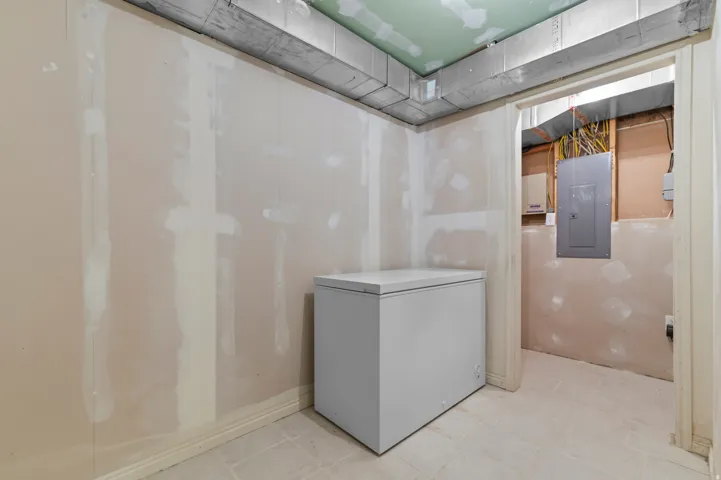 Exposed ductwork, unfinished drywall, and a utility access area featuring an electrical panel