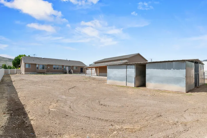 Expansive rear grounds featuring a detached shed, a covered structure, and a perimeter fence