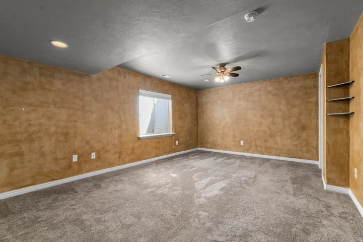 Recessed lighting, ceiling fan, carpet flooring, built-in shelving, and a window
