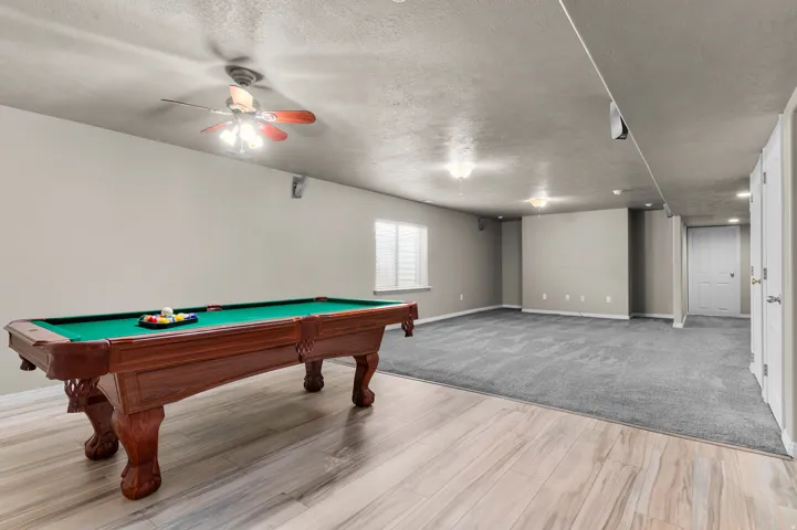 Expansive recreation area featuring wood-finish flooring and carpet, recessed lighting, and a textured ceiling