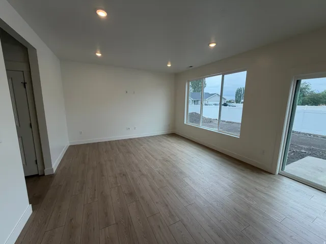 Recessed ceiling lighting, wood-finish flooring, large windows, and a sliding glass door