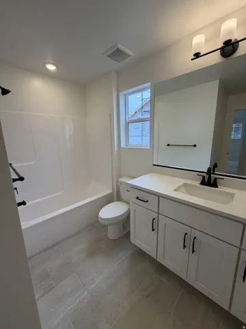 Bathroom featuring a single vanity with white cabinetry, a white countertop with an integrated sink, and matte black fixtures