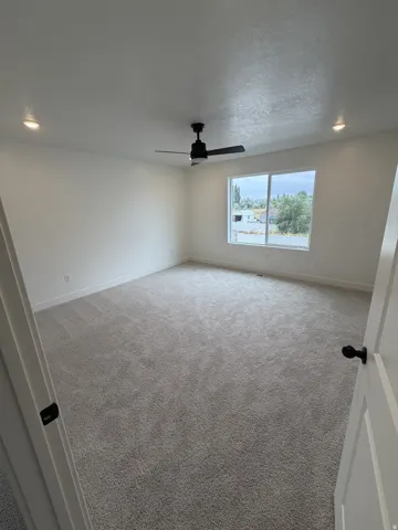 Recessed lighting, ceiling fan with light fixture, large window, and light-toned carpeting